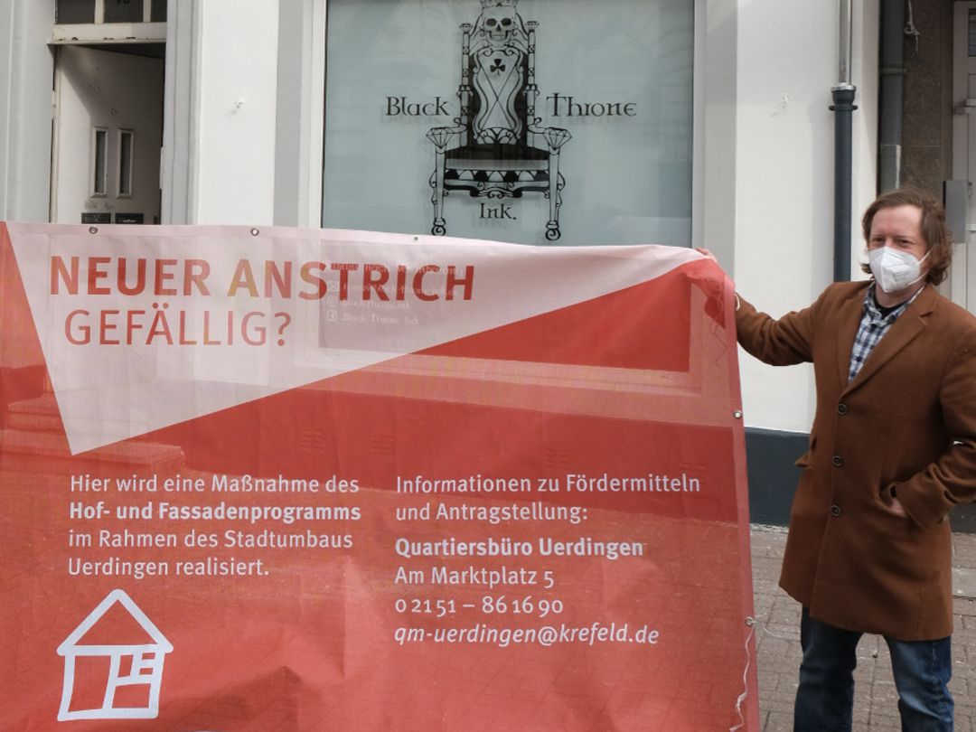 Der Eigentümer Christopher Dahlen steht vor seinem Objekt in der Oberstraße 43, dessen Fassade gerade mit öffentlichen Fördermitteln saniert worden ist. In der Hand hält er ein Transparent zur Bewerbung des Förderprogramms mit dem Slogan Neuer Anstrich gefällig?