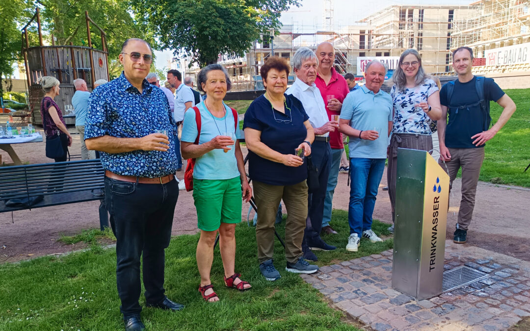 Mitglieder des Stadtumbaubeirats stehen vor dem Trinkwasserbrunnen in den Rheinanlagen